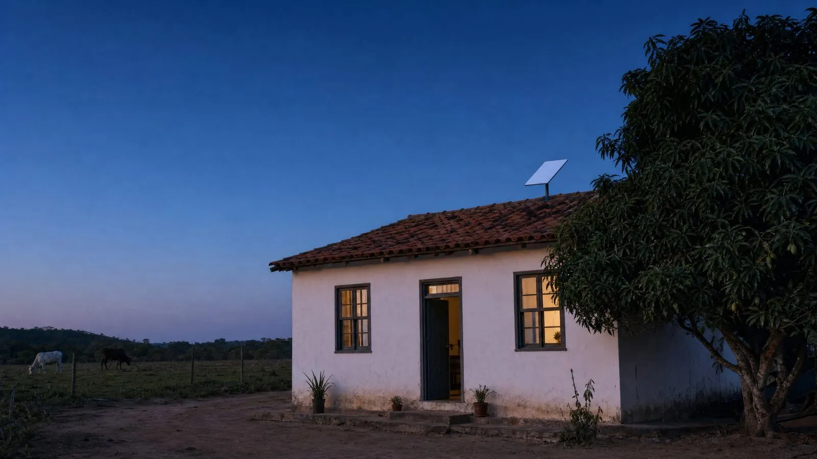 Sítio no interior do Brasil ao anoitecer, casa simples de paredes brancas e telhado de barro, com antena Starlink instalada no telhado
